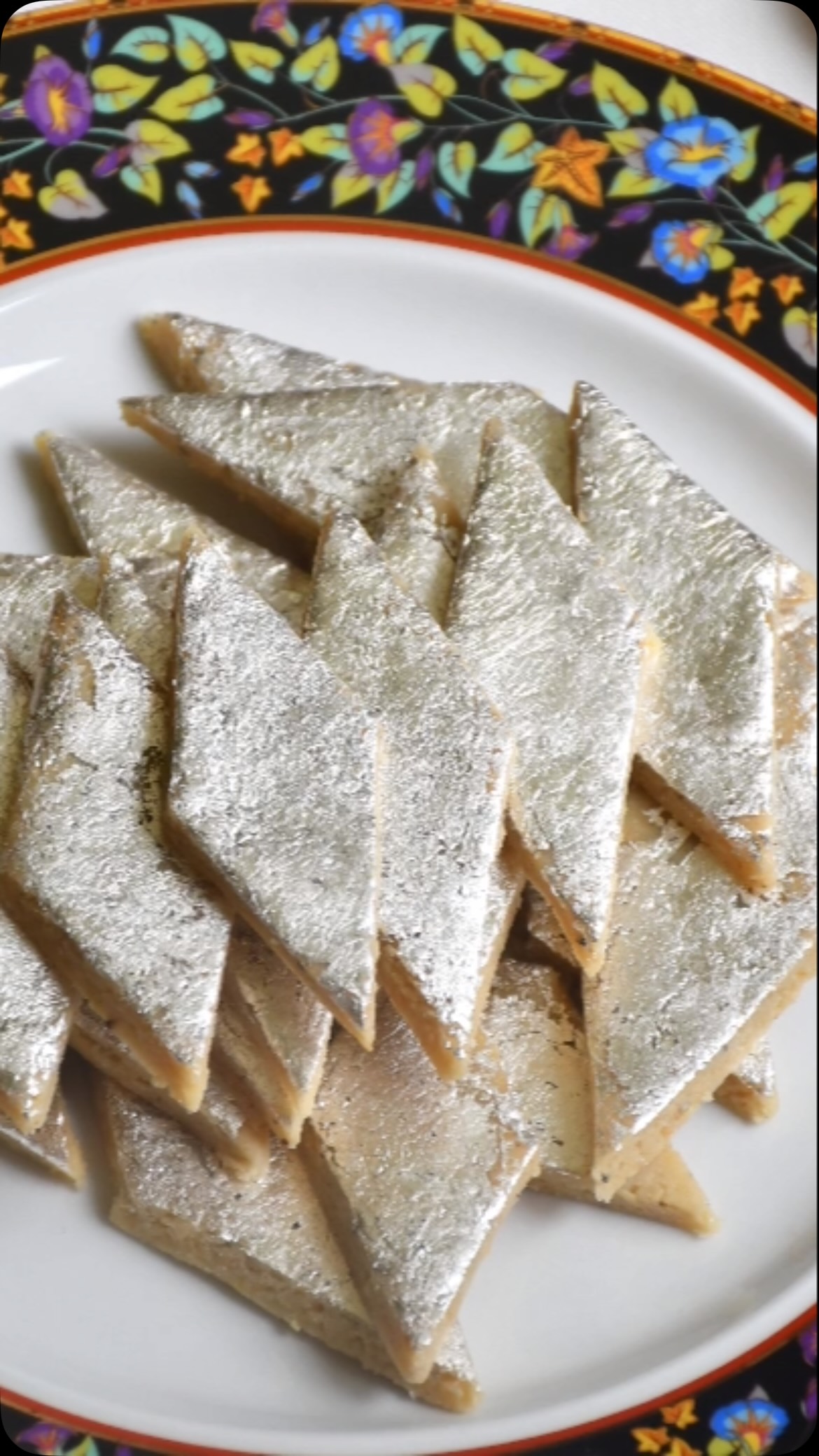 #kajukatli😍 #kaju❤️ #Kaju (Cashewnut) Katli is probably the most popular sweets in India. It is the most bought and gifted sweets during festival season and for other occasions. People always admire it if you serve or give a gift of Kaju Katli . General thinking is that kaju katli is difficult  to make at home but surprisingly it is very quick and easy to make. Just follow my recipe step by step and you can make Kaju katli that tastes and looks similar to that sold at large sweet shops. No one will believe that it is homemade. 
 
Ingredients:
Make 500 gm.

250 gm Kajus (Full or split or broken)
50 gm. milk powder
160 gm. Sugar
100 ml water
Saffron (optional)
Edible silver/  chandi varak (Optional for garnish)
One thick plastic sheet, or parchment paper for rolling 

Method:
Place Kajus, about 1/2 cup at a time, in the food processor. Pulse until you reach a flour-like consistency; sift into a container. Place any remaining Kaju chunks back into the food processor and pulse. Repeat until all Kajus are transformed into flour. Make sure you do not pulse too much else Kajus will release fat making it non suitable for the recipe.. 
Mix Kaju flour and dry milk in a container. 
To prepare sugar syrup, add sugar, water and saffron in a shallow pot and heat on low-medium flame. Heat for about 3 to 5 minutes till large bubbles start rising and you see two threads when you take a drop of syrup and pinch between two fingers and release fingers. Stir often.
Turn off the heat and add Kaju - milk powder mix to the syrup. Mix everything very well so that it becomes like dough. Spread it in the pan and let rest it cool. Dough should be firm and stiff. If it is sticky, add Kaju flour one spoon at a time to make it firm and stiff.
Remove the dough and knead it for about 2-3 minutes by keeping it in between thick plastic sheets. 
Keep the dough between plastic sheet and roll the dough into a flat sheet about ¼ inch thickness (like a big chapati)
Wait for about 5 minutes and garnish with edible silver foil (silver varak) and cut into diamond shapes of desired size.
Keep it in the refrigerator for about an hour for it to set.
Store it in the refrigerator.

Enjoy!