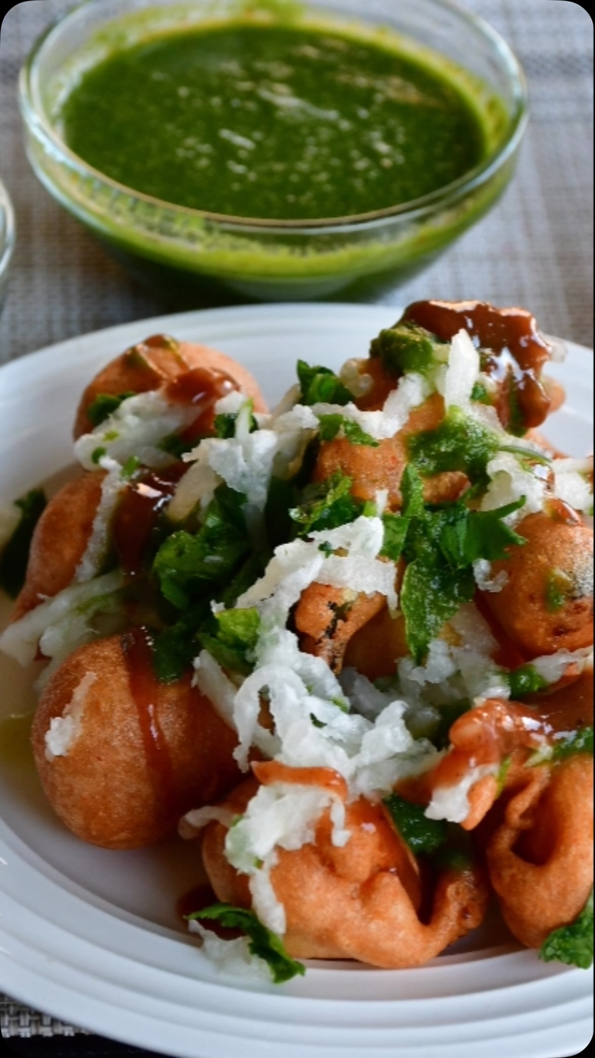 #ramladduAll south asians love to eat chaat (spicy street food)#ramladduyum😋😋 
anIngredients:
Serves: 4 or more 
I cup yellow moong dal
½ cup yellow chana dal 
½ cup white urad dal 
2-3 green chili 
1 inch ginger 
2 tsp red chili powder 
2 tsp whole dry coriander seeds (optional)
1 tsp fennel seeds (optional)
Pinch of hing (asafoetida) 
1 large mooli (Daikon/ Radish) grated 
Lemon juice (1 lemon) 
Oil for frying 
Salt to taste 

For chutney
1 cup coriander leaves
⅓ cup mint
2 green chili 
½ tsp black pepper 
½. inch ginger - chopped
1 tsp cumin seeds 
1 inch of mooli (optional) 
1 lemon juice 
1 tsp sugar 

Method for chutney: 
Add all ingredients in the blender with ⅓ cup of water and make a paste. Add water, if required. Keep aside. 
Method for pakoras: 
Wash all dals (lentils) under running water and soak for about 7 to 8 hours. 
Add lentils, hing,whole coriander(optional), red chili powder, green chili, ginger to the blender (Use processor, if you have one) and make a paste.
Heat oil in a frying pan (medium heat)
Meanwhile mix the dal batter using your hands for about 5 minutes to make it fluffy (Air in the mix makes pakoras crisp & soft and consumes less oil). Add fennel seeds and salt.
Now take a chunk of the mix (Use hands or a spoon) and drop it in hot oil and make pakoras.  Fry on medium heat till golden brown. Do not overcrowd by putting too many pakoras together. Stir often. 
Transfer on paper towels to soak excess oil. Repeat till you consume dal batter. 
Take a bowl, add grated radish(mooli), salt and lemon juice. If you like, you can add chopped radish/ mooli leaves also. Keep aside 
For serving, take a plate, add radish/ mooli mix, put 4-6 hot pakoras on top. Serve with green chutney on the side. 

Enjoy this month watering recipe. 

Note : You can also add green chili pakora. For this, take any variety of chill, cut vertically in the center, dip in the dal batter and fry. Serve with dal pakoras (4-6 dal pakoras/ 1-2 green chilli