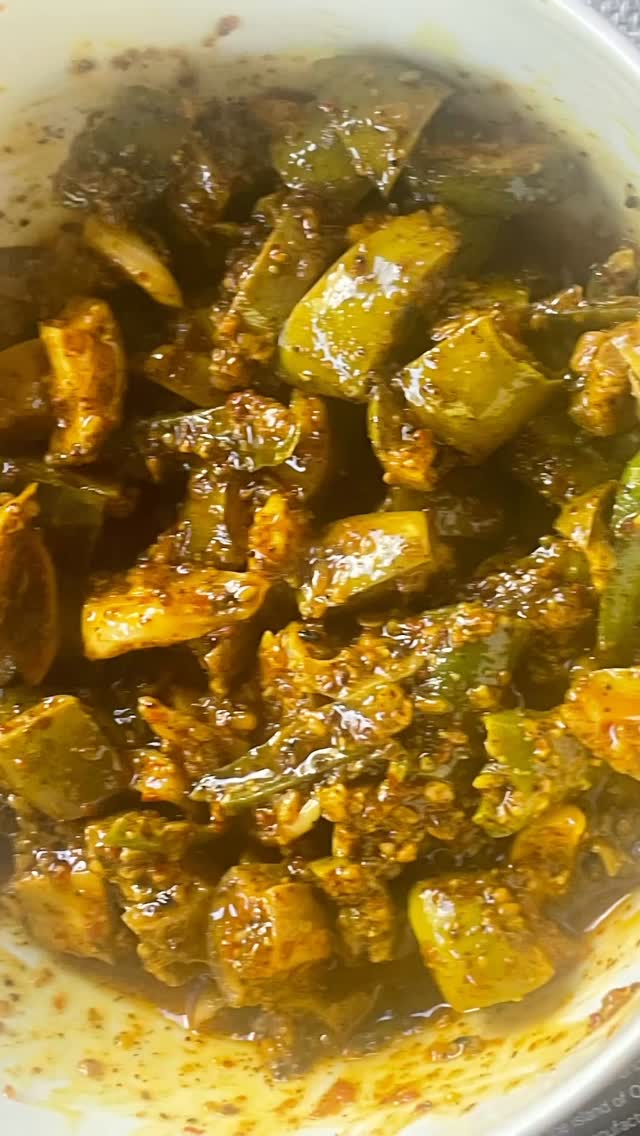#mangochlie #pickle#Green Mango Pickle with Garlic and Green Chili is a bold, rustic Indian pickle that captures the essence of early summer. Made with firm, unripe mangoes, this pickle balances tanginess, heat, and aromatic spices in a way that instantly elevates any meal. The sharp bite of fresh green chilies, the earthy warmth of garlic, and the deep flavors of mustard seeds and oil come together to create a pickle that is both vibrant and addictive.
Ingredients
2 cups raw green mangoes (firm, sour)

12–15 green chilies
1 whole garlic bulb (about 15–20 cloves)
3 tbsp salt
2 tbsp red chili powder 
1 tbsp turmeric powder
2 tbsp mustard seeds
2 tbsp fenugreek seeds
2 tbsp fennel seeds (optional)
1 tsp asafoetida (hing)
1 tbsp nigella seeds (kalonji).
1 to 1½ cups mustard oil 
Juice of 1 lemon (optional)
Preparation
1. Prep the vegetables

Wash and dry mangoes and chillies completely.
Cut mango into small cubes ~ ½ inch (keep peel if tender).
Slit or chop green chilies.
Peel garlic cloves and cut large cloves into pieces.
Moisture shortens pickle life, so make sure ingredients are fully dry.
2. Roast spices
Dry roast on low flame for 2-3 minutes 
Fenugreek seeds
Mustard seeds
Fennel seeds (if using)
Nigella seeds (if using)
Cool and crush lightly.
3. Mix, In a large bowl combine:Mango, chilies,garlic, salt,tumeric, red chili powder, roasted and crushed spices.  Mix very well.
4. Heat oil
Heat mustard oil until it just starts smoking lightly (Do not heat till it smokes fully, else color will darken), then cool until warm.
Pour over the pickle mixture and stir well.
5. Mature the pickle: Transfer to a clean dry glass jar. Keep on sun for 3 to 5 days.
The mango softens and absorbs flavors over time.
Storage:Always use a dry spoon