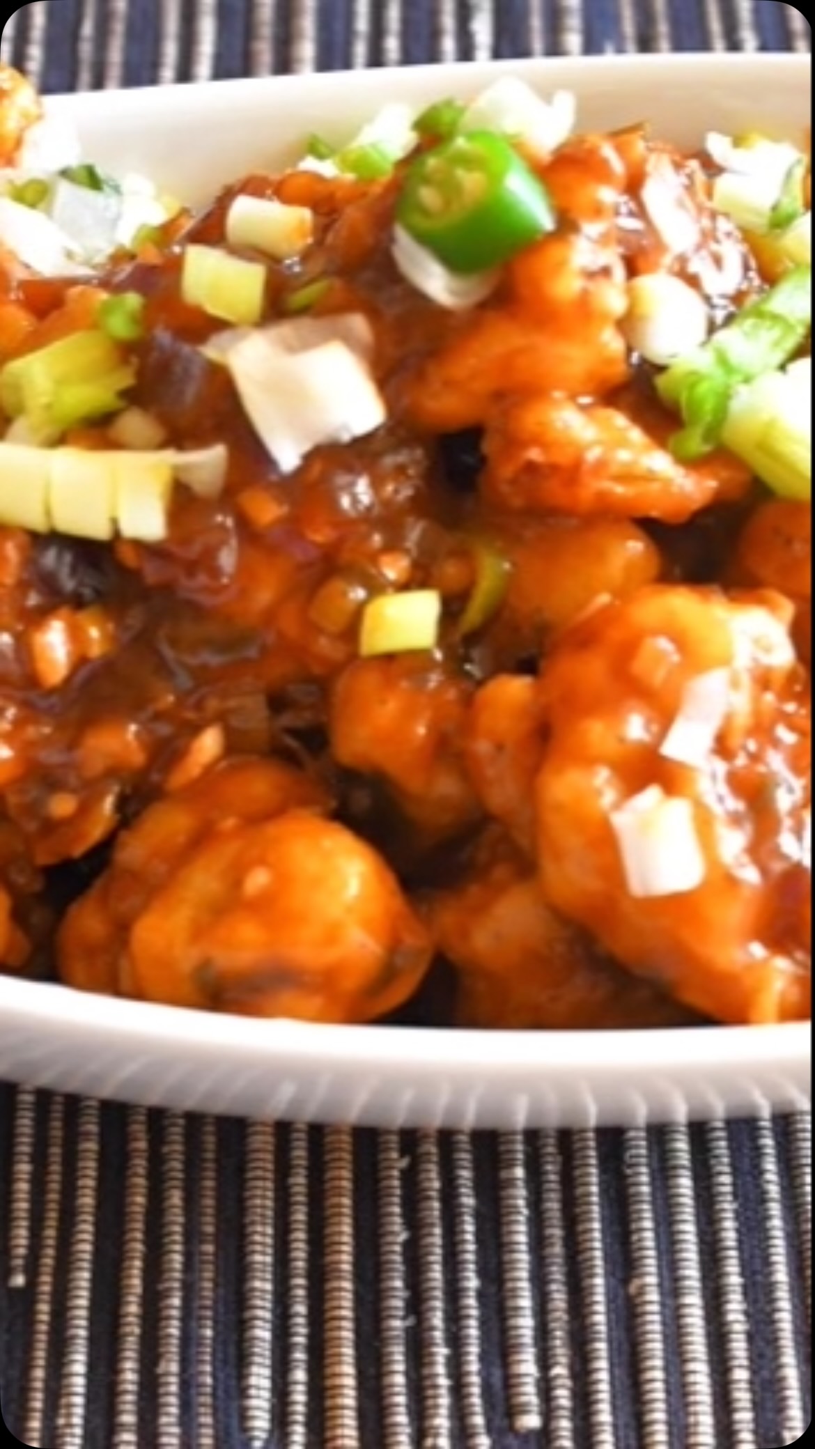 #gobhimanchurian #gobhirecipe #Here is an Indo-Chinese version of preparing (Cauliflower) called Gobhi manchurian. It is a very delicious recipe and surprisingly not very difficult to make. When you serve and eat, it is worth all the effort.

Ingredients: 
Serves: 4 or more 

1 medium cauliflower -  cut into small florets (~1 sq inch) 
5 tbsp all purpose flour 
5 tbsp cornstarch
2 tsp salt (Adjust to taste) plus additional for flour mix 
Oil for frying 
For the sauce:
3 tbsp oil
3 tbsp garlic - finely chopped 
2 green chilies -  finely chopped (adjust to taste) 
1 medium onion - finely chopped 
4 tbsp soya sauce
1 tbsp red (hot) chili sauce (Adjust to taste)
1 tbsp tomatoes ketchup
Salt - to taste 
2 tsp cornstarch 
I cup water
Spring onion - for sauce as well as for garnish

METHOD 
For gobhi 
 Take a pot and add  4 cups of water with 2 tsp salt, wait until water starts boiling.
Add gobhi, and boil for about 3 or 4 minute
on medium heat.
Strain gobhi and let it sit for 3 to 5 minutes. 
Take a bowl, and add corn flour, all purpose flour,  salt to taste and make a thick paste (with consistency similar to tomato ketchup) . 
Heat the oil in a  frying pan on medium heat. 
Dip gobhi florets into flour  mix and coat it fully. Fry one or two florets into hot oil and check to make sure that flour mixture is notseparated from florets. If it does, add 1 tsp all purpose flour,  1 tsp cornstarch and salt (If required, add additional flour) into the flour mix to make it thicker. 
Fry all of the florets (till golden in color) and keep aside.
Optionally, to make gobhi florets crispier, fry it once till semi fried. Let it cool and fry it again on high flame till golden in color.
For the sauceTake a wok and add oil, wait until hot then put garlic, onion, green chillies and add a little bit of salt.
After about a minute, add soya sauce, red chilli paste and ketchup, stir in the pan. 
Now add spring onions
Add 1 cup water. 
Take a small bowl, mix  2 tsp cornstarch mix in 3 tsp of  water and add to the wok
Stir till it becomes thick (tomato ketchup like consistency.If required, add more cornstarch or water as necessary. Put off the flame , take big wide bow and add fried gobhi .
