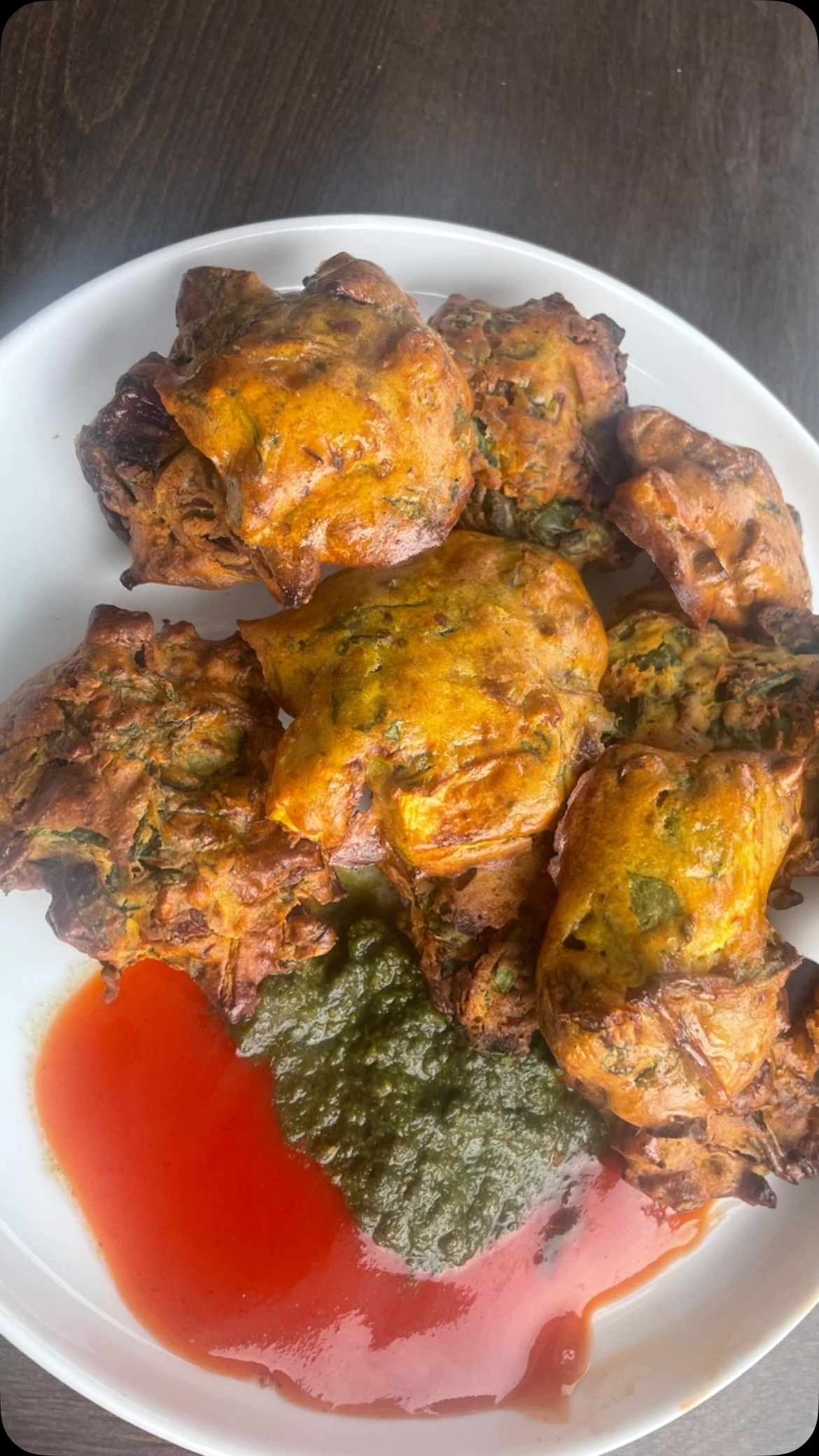 #airfrypakora#Few foods carry the kind of soul-warming nostalgia that pakoras do. Across India, these crispy#spiced fritters have graced #street food carts, family kitchens, and roadside dhabas for generations. Pakoras are synonymous with the monsoon season — the kind of snack you reach for when rain is hammering the windows and a cup of chai is already brewing on the stove.

This air fryer version is a #game-changer. You get the same deeply spiced, shattering crunch on the outside and a soft, steamy interior — without the liters of oil, the splatter, or the lingering smell -  ready in under 30 minutes! No frying. Eat guilt free and enjoy any time. Simple and tasty.

Ingredients 
2 cups palak (spinach) - washed, dried and finely chopped
1 small onion - finely chipped
2  green chilies - finely chopped (adjust as per taste)
1 cup besan (gram flour)
1 tbsp rice flour/ corn flour ( optional, for extra crisp)
1 tsp ajwain (carom seeds)
1 tsp red chili powder (adjust as per taste)
½ tsp turmeric powder 
1 tsp garam masala 
Salt to taste
Oil for brushing or spray

Method

In a bowl, add besan, palak, onion, rice flour, green chilies and spices
Mix well and let it rest for a few minutes since spinach and onions will release water. Add extra water (little at a time) to make a thick batter( pakora - style). Mix very well. 
Keep aside  for 15 minutes. 
Preheat air fryer @ 190 C or 375 F 
Lightly grease the air fryer or put on parchment paper. Mix pakora mix, shape pakora with a spoon or hand and put in an air fryer. Keep space in between and do not over crowd.
Bake for 5-7 minutes,  then apply oil on top with a brush or spray. 
Bake for 5-7 minutes or until golden brown.
Flip pakoras, apply oil on reverse side and bake for another 5-7 minutes
Serve with green chutney, imli chutney and masala chai

Note: Skip onion if you want something only palak pakoras, 
Add grated lauki/ ghiya/ dudhi (opo squash)  or zucchini for extra softness
You can try different pakoras, just replace spinach and onion with cauliflower or eggplant or  potatoes etc. 
Batter needs to be thick else it will spread thin inside air fryer
