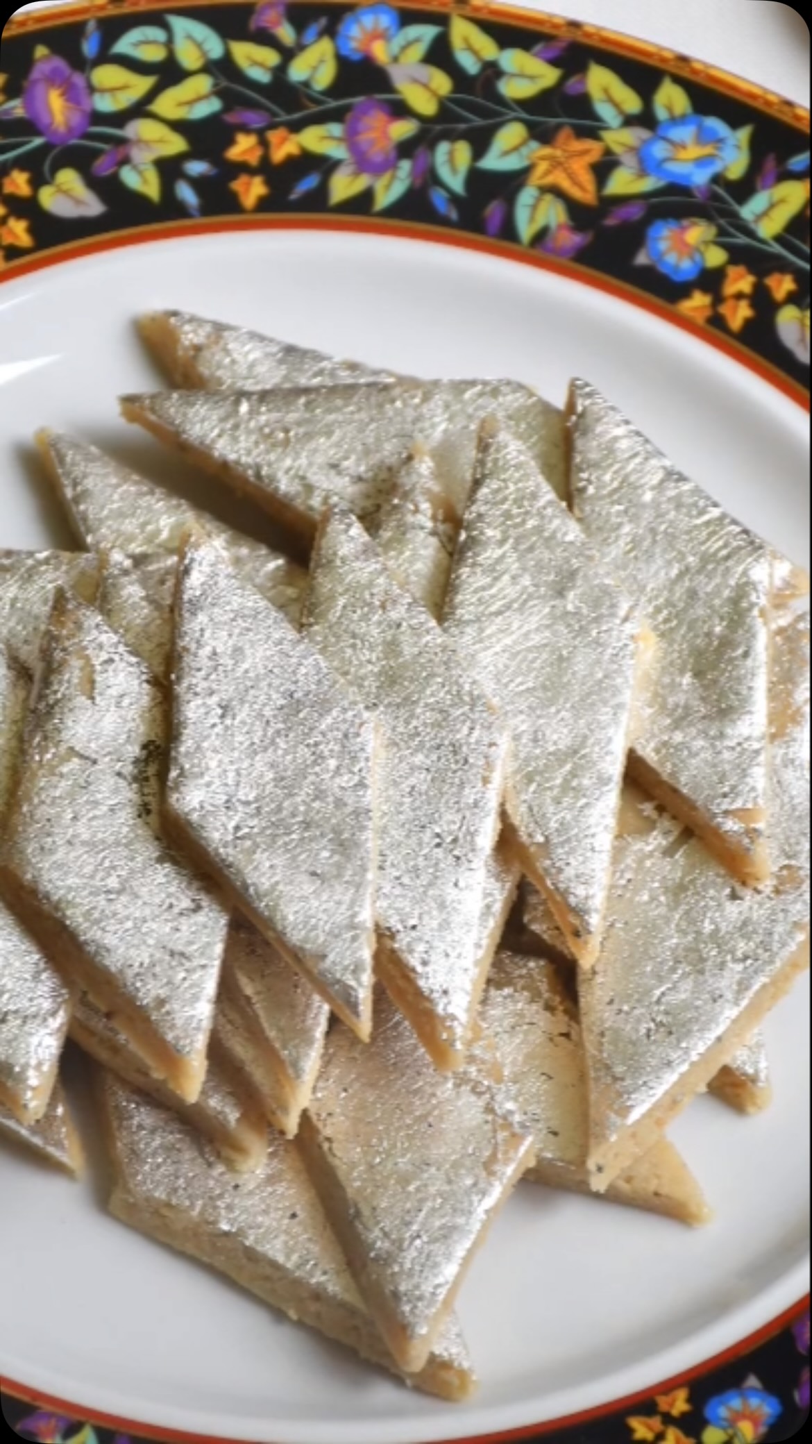 #Kaju (Cashewnut) Katli is probably the most popular sweets in India. It is the most bought and gifted sweets during festival season and for other occasions. People always admire it if you serve or give a gift of Kaju Katli . General thinking is that kaju katli is difficult  to make at home but surprisingly it is very quick and easy to make. Just follow my recipe step by step and you can make Kaju katli that tastes and looks similar to that sold at large sweet shops. No one will believe that it is homemade. 
 
Ingredients:
Make 500 gm.

250 gm Kajus (Full or split or broken)
50 gm. milk powder
160 gm. Sugar
100 ml water
Saffron (optional)
Edible silver/  chandi varak (Optional for garnish)
One thick plastic sheet, or parchment paper for rolling 

Method:
Place Kajus, about 1/2 cup at a time, in the food processor. Pulse until you reach a flour-like consistency; sift into a container. Place any remaining Kaju chunks back into the food processor and pulse. Repeat until all Kajus are transformed into flour. Make sure you do not pulse too much else Kajus will release fat making it non suitable for the recipe.. 
Mix Kaju flour and dry milk in a container. 
To prepare sugar syrup, add sugar, water and saffron in a shallow pot and heat on low-medium flame. Heat for about 3 to 5 minutes till large bubbles start rising and you see two threads when you take a drop of syrup and pinch between two fingers and release fingers. Stir often.
Turn off the heat and add Kaju - milk powder mix to the syrup. Mix everything very well so that it becomes like dough. Spread it in the pan and let rest it cool. Dough should be firm and stiff. If it is sticky, add Kaju flour one spoon at a time to make it firm and stiff.
Remove the dough and knead it for about 2-3 minutes by keeping it in between thick plastic sheets. 
Keep the dough between plastic sheet and roll the dough into a flat sheet about ¼ inch thickness (like a big chapati)
Wait for about 5 minutes and garnish with edible silver foil (silver varak) and cut into diamond shapes of desired size.
Keep it in the refrigerator for about an hour for it to set.
Store it in the refrigerator.
More recipes on my website.
Enjoy!
